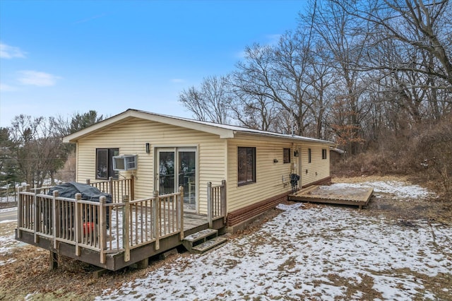 snow covered house featuring a wooden deck and a wall mounted air conditioner