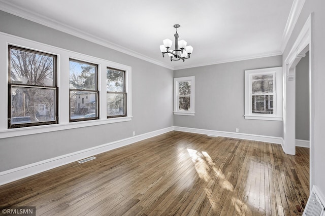 unfurnished dining area featuring hardwood / wood-style flooring, ornamental molding, and a chandelier