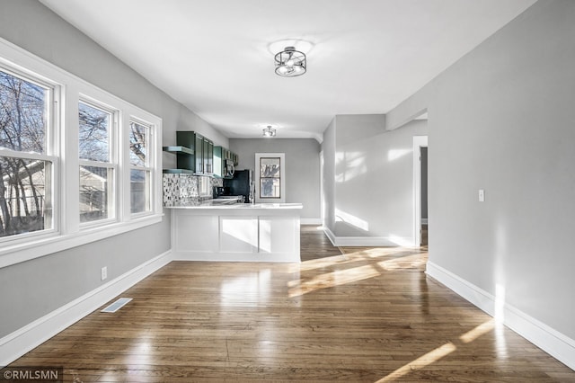 interior space with dark wood-type flooring, black fridge, kitchen peninsula, and green cabinets