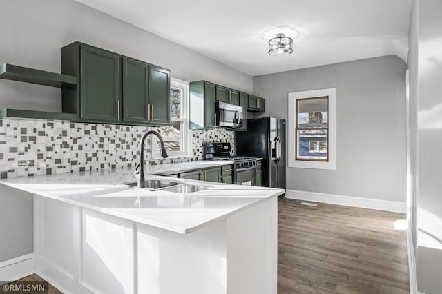 kitchen featuring tasteful backsplash, black appliances, kitchen peninsula, and green cabinets