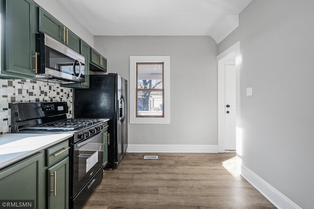 kitchen featuring wood-type flooring, green cabinets, black range with gas stovetop, and decorative backsplash