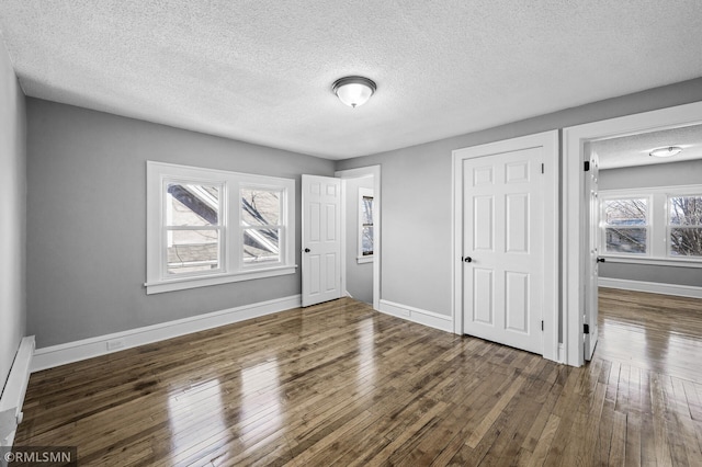 unfurnished bedroom featuring dark hardwood / wood-style flooring and a textured ceiling