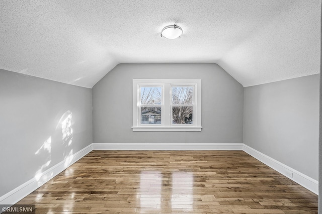 bonus room featuring hardwood / wood-style flooring, vaulted ceiling, and a textured ceiling