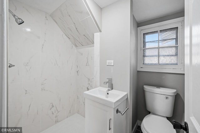 bathroom featuring vanity, toilet, and tiled shower