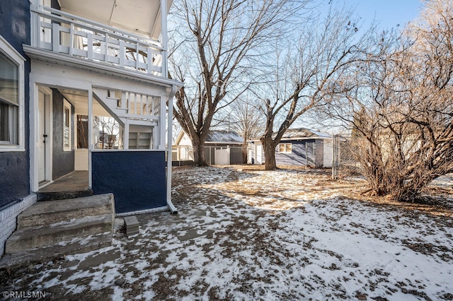 yard covered in snow with a balcony and a shed