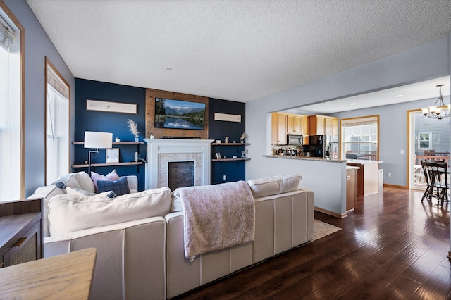 living room featuring dark wood-type flooring, a notable chandelier, and a textured ceiling