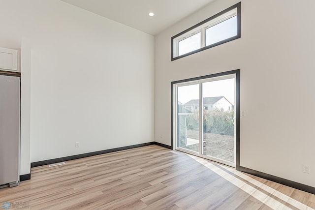 spare room with a towering ceiling and light hardwood / wood-style floors