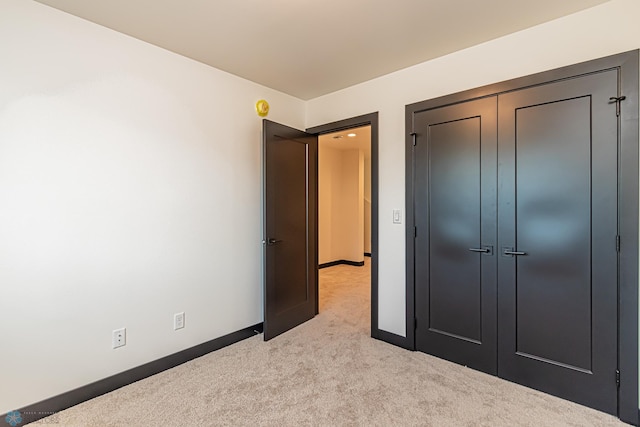 unfurnished bedroom featuring light colored carpet and a closet