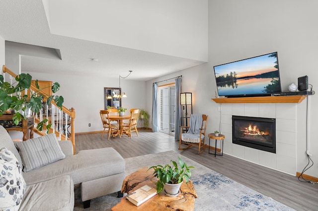 living room featuring hardwood / wood-style flooring, a tile fireplace, and a notable chandelier