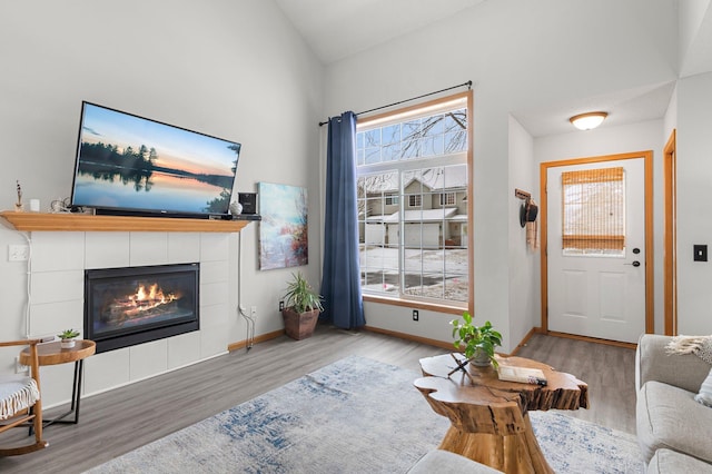 living room featuring lofted ceiling, a tiled fireplace, and light hardwood / wood-style floors