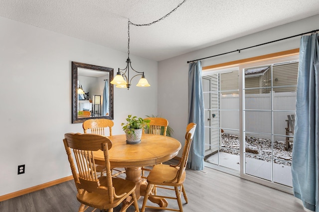 dining area with a chandelier, a textured ceiling, and light wood-type flooring