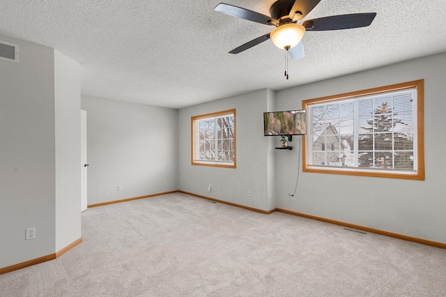 spare room with ceiling fan, light carpet, and a textured ceiling