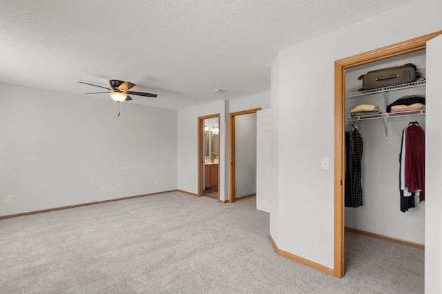 unfurnished bedroom featuring a walk in closet, ceiling fan, light carpet, a textured ceiling, and a closet