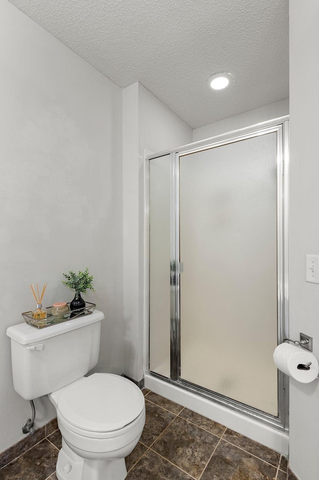 bathroom featuring a shower with shower door, a textured ceiling, and toilet