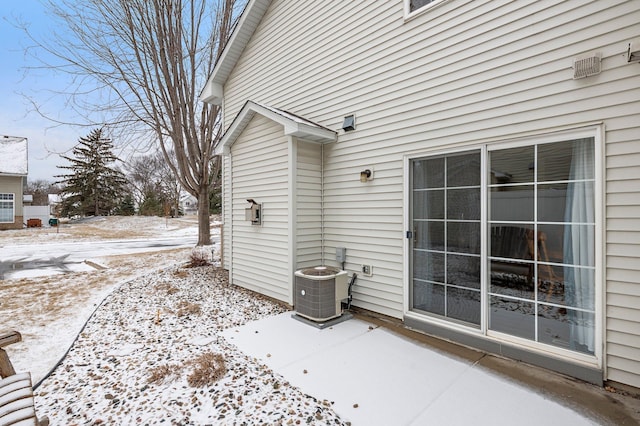 view of snowy exterior featuring a patio and central air condition unit