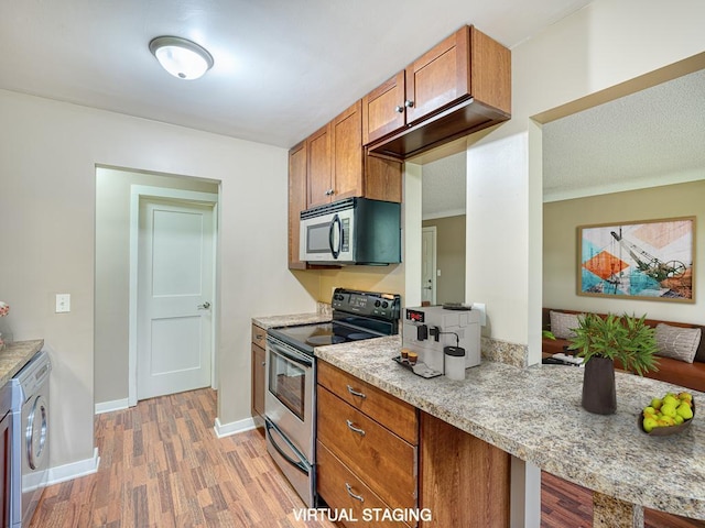 kitchen featuring stainless steel appliances, light wood-type flooring, and washer / clothes dryer