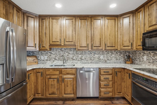 kitchen featuring sink, black appliances, dark hardwood / wood-style floors, light stone countertops, and backsplash