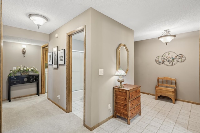 hallway with light carpet and a textured ceiling