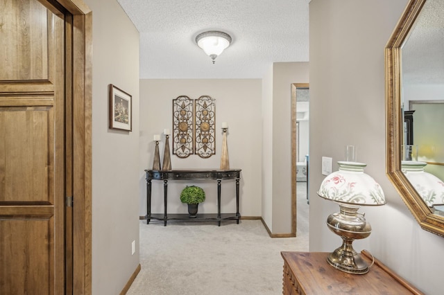 hall featuring light carpet and a textured ceiling