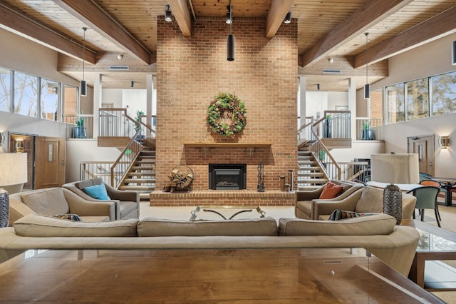 living room with a high ceiling, wooden ceiling, a fireplace, and beam ceiling