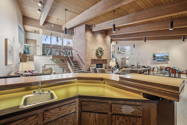 kitchen with sink, track lighting, a brick fireplace, wooden ceiling, and beamed ceiling