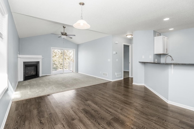 unfurnished living room featuring sink, ceiling fan, a textured ceiling, dark hardwood / wood-style flooring, and vaulted ceiling