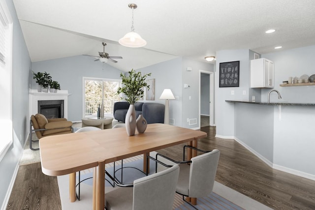 dining area featuring lofted ceiling, dark wood-type flooring, sink, and ceiling fan