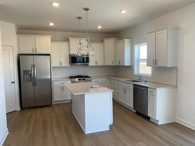 kitchen with a kitchen island, white cabinetry, sink, hanging light fixtures, and stainless steel appliances