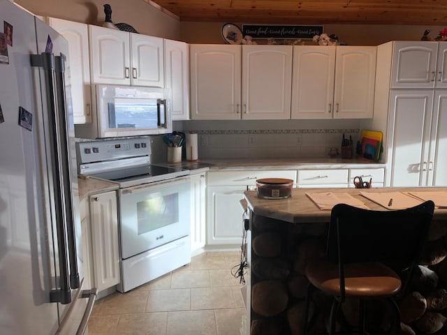 kitchen featuring tasteful backsplash, white cabinetry, light tile patterned flooring, and white appliances