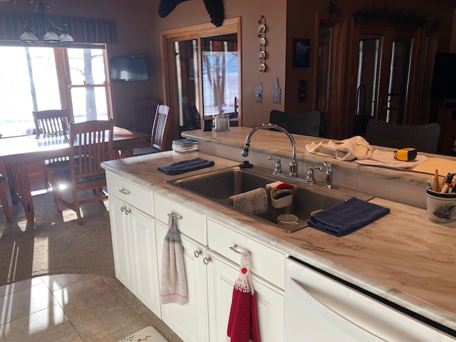 kitchen with dishwasher, sink, light carpet, and white cabinets