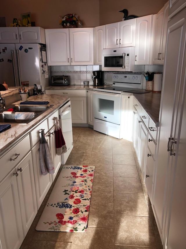 kitchen featuring tasteful backsplash, white appliances, sink, and white cabinets