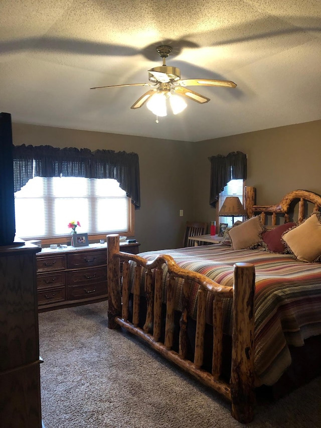 carpeted bedroom featuring ceiling fan and a textured ceiling