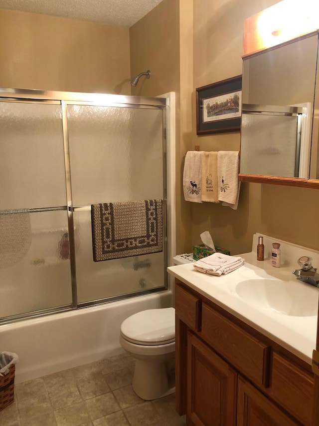 full bathroom featuring vanity, a textured ceiling, toilet, and combined bath / shower with glass door