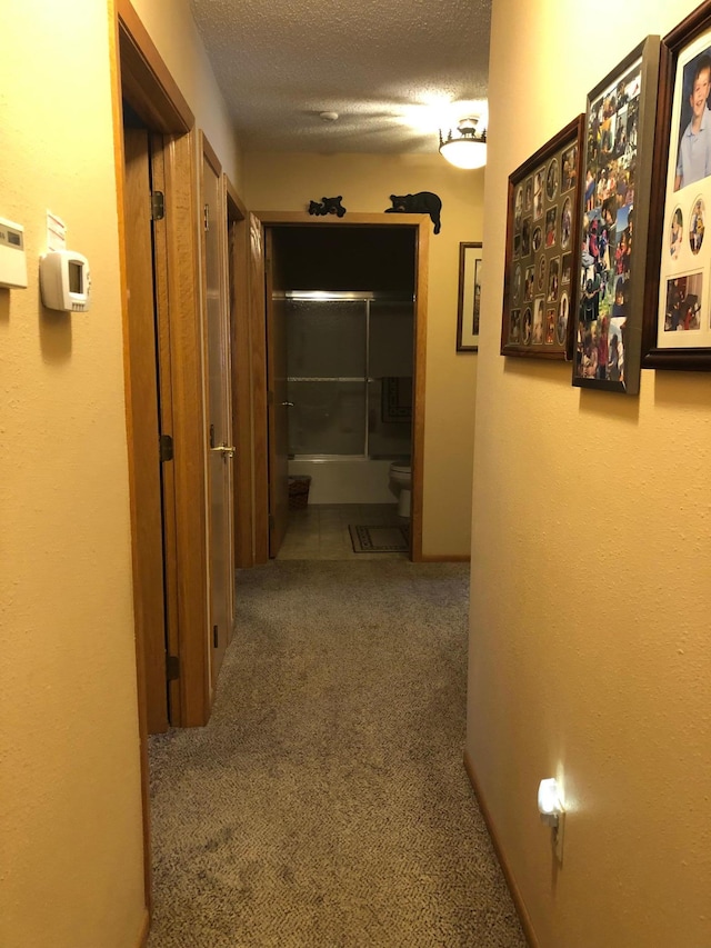 hallway with carpet flooring and a textured ceiling