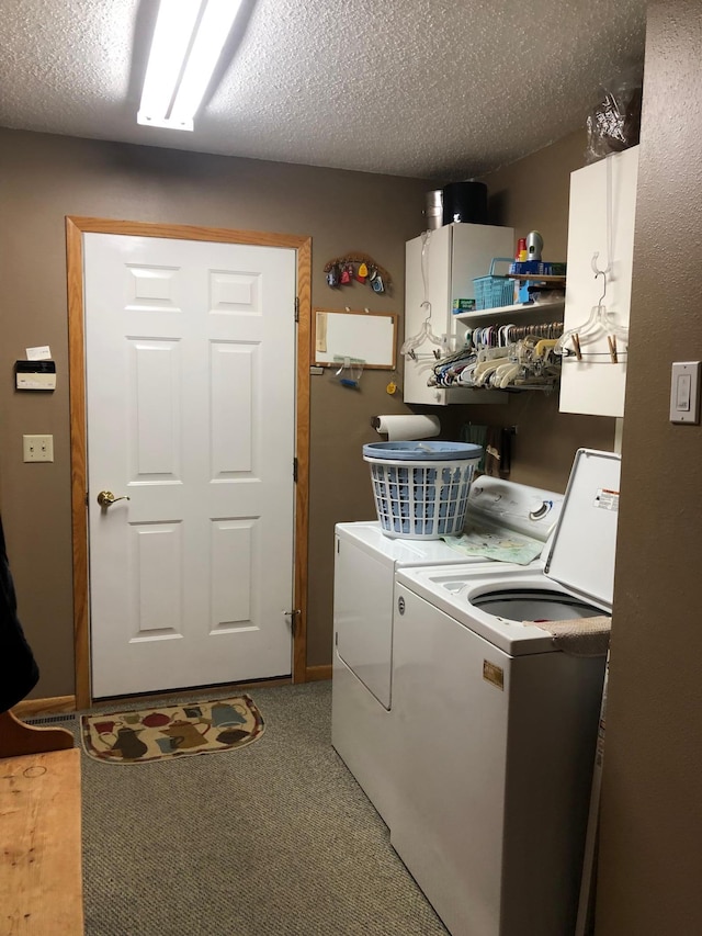 laundry area featuring cabinets, washing machine and dryer, carpet flooring, and a textured ceiling