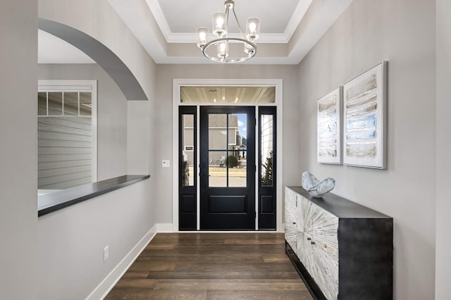 foyer featuring dark hardwood / wood-style floors, ornamental molding, and a raised ceiling