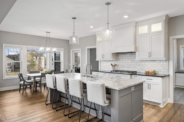 kitchen featuring decorative light fixtures, sink, a center island with sink, and white cabinets