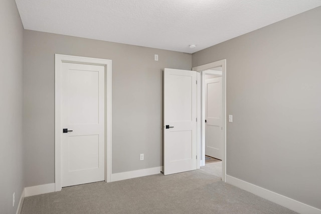 unfurnished bedroom featuring light carpet and a textured ceiling