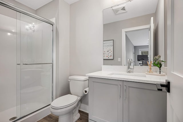 bathroom featuring vanity, toilet, a shower with door, and wood-type flooring