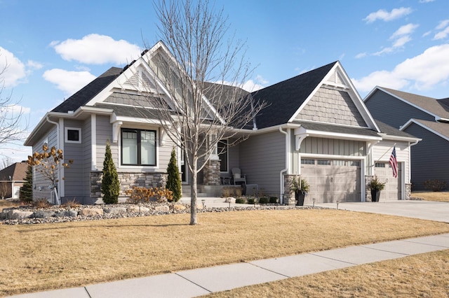 craftsman inspired home with an attached garage, stone siding, a front yard, driveway, and board and batten siding