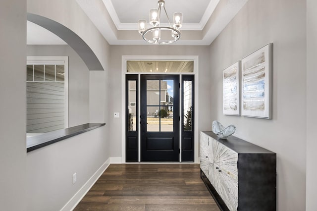 foyer with a chandelier, arched walkways, dark wood finished floors, and crown molding