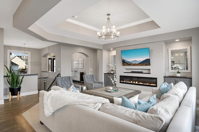 living room with a chandelier, a tray ceiling, arched walkways, and dark wood-style flooring