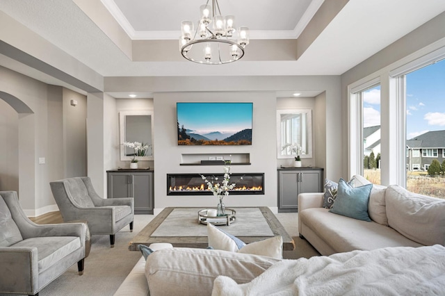 living room featuring a glass covered fireplace, arched walkways, light carpet, a chandelier, and a raised ceiling