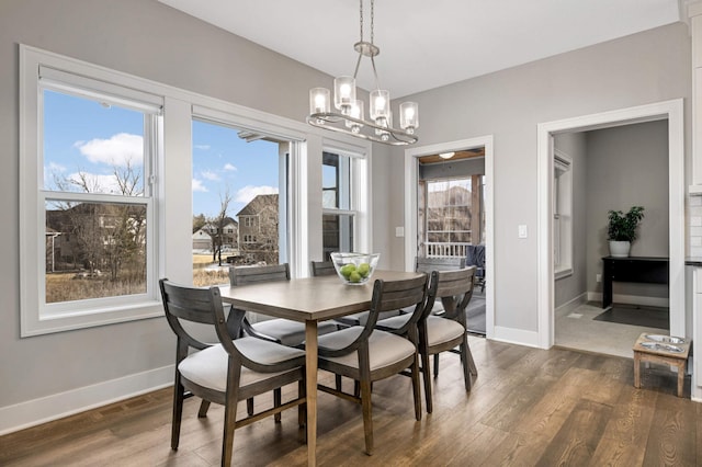 dining room with a chandelier, dark wood-style flooring, and baseboards