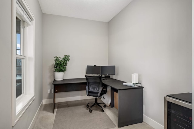 carpeted home office featuring wine cooler and baseboards