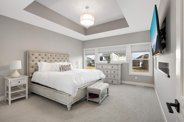 bedroom with baseboards, light colored carpet, and a raised ceiling