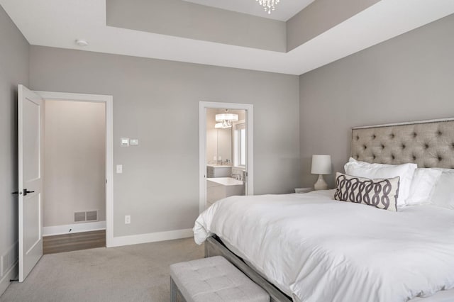 bedroom with a chandelier, carpet flooring, baseboards, connected bathroom, and a tray ceiling