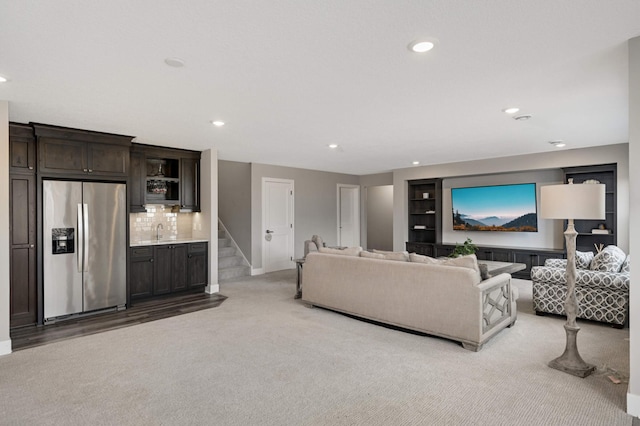 living area with light carpet, baseboards, recessed lighting, stairs, and built in features