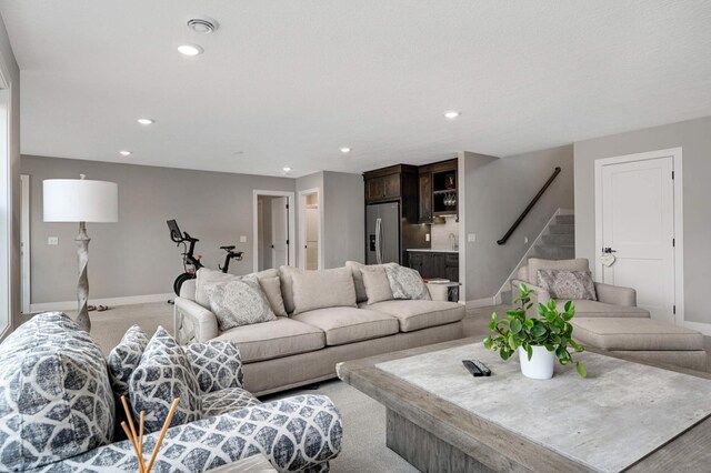 living room featuring baseboards, recessed lighting, and stairway
