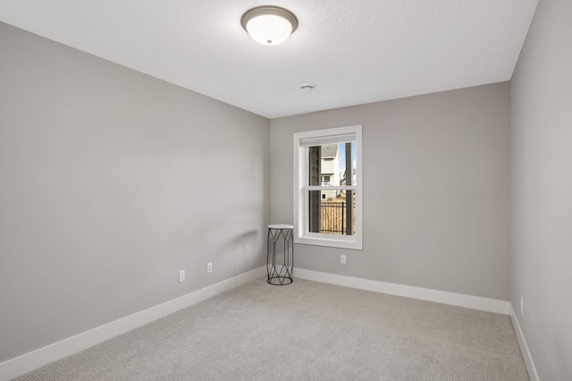 carpeted empty room with baseboards and a textured ceiling
